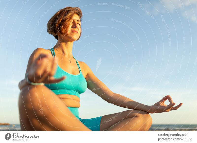 Eine Frau macht Meditationsübungen am Strand, nach einer Pilates-Sitzung bei Sonnenuntergang Yoga mediterran Spanien Fitness Gesundheit echte Menschen Lifestyle