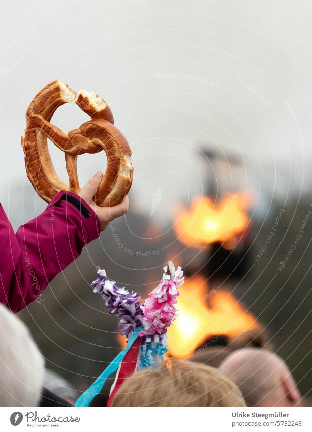 Ein Kind hält eine angebissene Brezel dahinter brennt ein Schneemann, der den Frühlingsanfang symbolisiert Sommertagsumzug Speyer Pfalz Rheinland-Pfalz Kinder