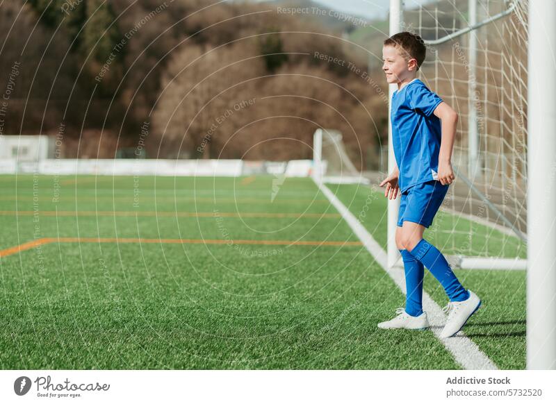 Junger Fußballspieler auf dem Spielfeld, bereit für das Spiel Jugend Spieler Sport Uniform blau Tor grün Feld Kunstrasen stehen Fokus Kind Athlet im Freien