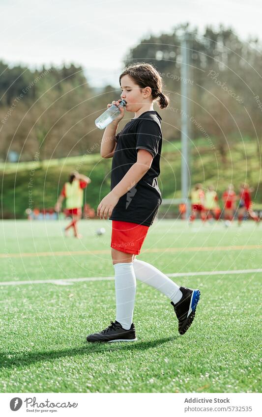 Junger Fußballspieler trinkt während des Trainings Mädchen Wasser Pause Hydratation Feld Sport Teamkollege Hintergrund üben jung sportlich trinken Gesundheit