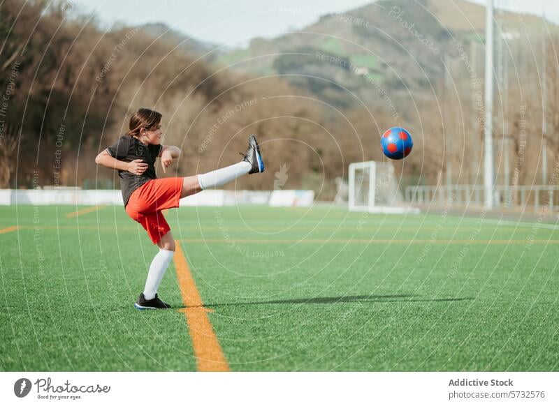 Ein junger Sportler übt auf dem Spielfeld Fußball Mädchen Jugend Athlet üben Fähigkeit Feld Ball Kick Rasen künstlich grün farbenfroh Berge u. Gebirge