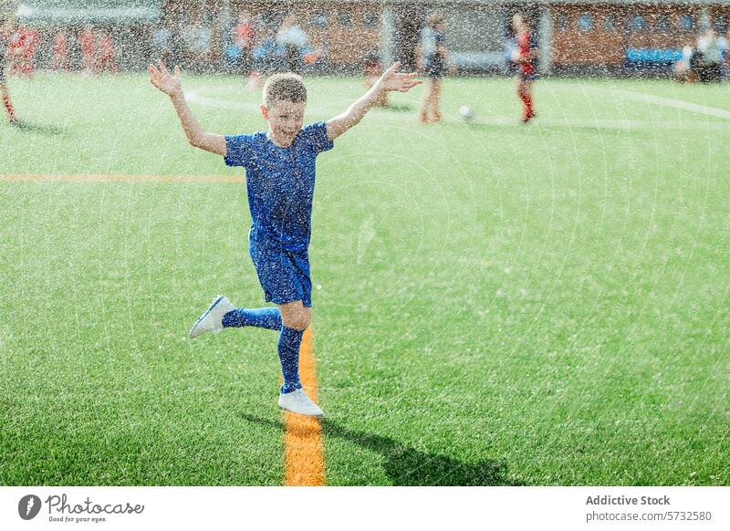 Fröhliches Kind beim Fußballspielen im Regen Freude Fröhlichkeit Sport im Freien Junge jugendlich Genuss aktiv Feld grün Gras Sportbekleidung Fußballer Spaß
