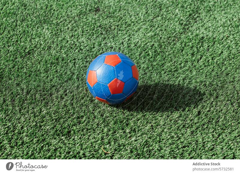 Bunter Fußball auf saftig grünem Kunstrasen Ball künstlich Rasen Gras Sport spielen im Freien Gerät Spiel Feld synthetisch Freizeit entspannend farbenfroh blau
