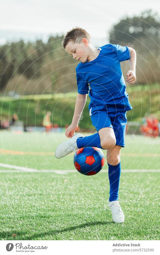 Junger Fußballspieler kontrolliert den Ball auf dem Feld Spieler Sport Kontrolle im Freien jung Kind Sportbekleidung blau Jugend Fähigkeit Athlet spielen Gras