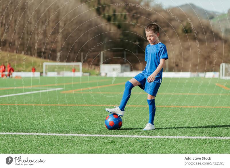 Junger Fußballspieler beim Üben auf dem Feld Spieler jung Sportbekleidung blau Fußballfeld Ball Torpfosten Hintergrund Training üben im Freien Jugend