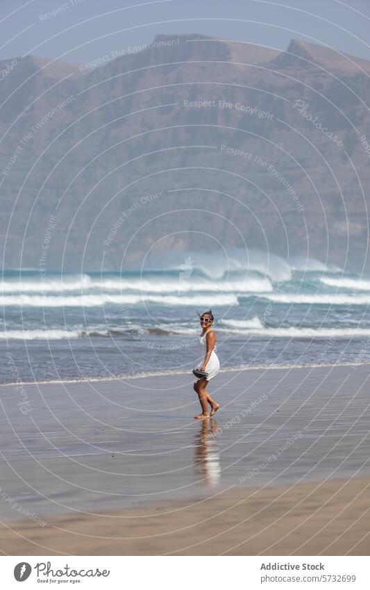Frau genießt einen friedlichen Spaziergang am Strand Meer Berge u. Gebirge Gelassenheit Wochenendausflug Freizeit sandig Wellen robust Hintergrund solo