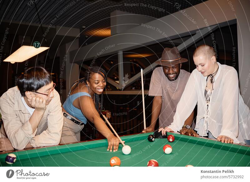 Verschiedene Gruppen junger Leute, die in einem Nachtclub Billard spielen und Spaß haben, aufgenommen mit Blitzlicht Menschengruppe schwarze Frau Freund Snooker