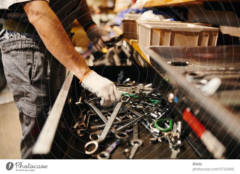Ausgeschnittenes Bild eines Mechanikers, der einen Schraubenschlüssel aus der Schublade nimmt Werkzeug wählen Schlamassel Hände Handschuh Reparatur Fahrzeug