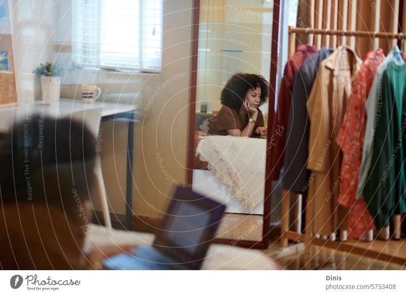 Reflexion einer Frau, die auf dem Bett liegt und am Laptop an einer Produktpräsentation arbeitet Präsentation Arbeit lernen Reflexion & Spiegelung Freiberufler