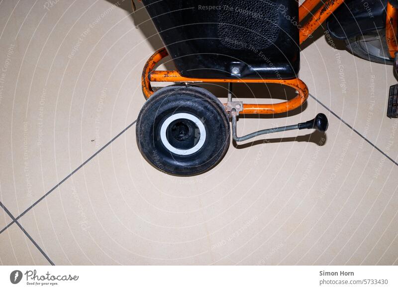 altes Dreirad mit kaputtem Hinterrad auf Fliesenboden Relikt Fortbewegung Kindheit Bremse spielen Spielzeug Rad rund fahren orange stabil Abnutzung Generationen