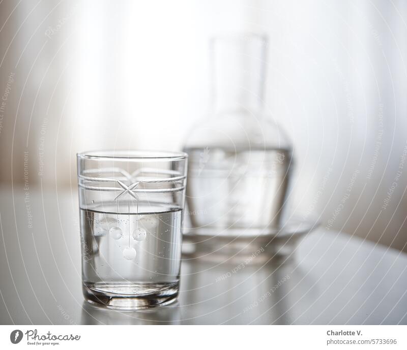 Klares, kaltes Wasser | geschliffenes Glas mit Wasser im Vordergrund, unscharfe Glaskaraffe im HIntergrund Karaffe Getränk Flüssigkeit Wasserglas Durstlöscher