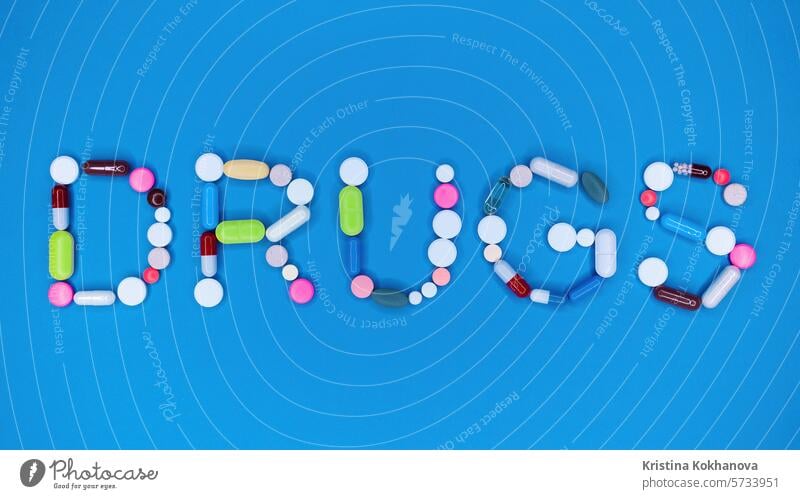 Mehrfarbige Kapseln in Wort Drogen. Blauer Hintergrund. Apotheke, Antidepressiva, Medizin-Konzept. Medikament Pharma medizinisch Gesundheit Antibiotikum