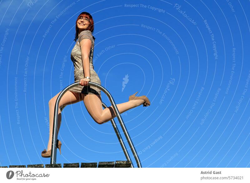 Eine junge Frau tanzt hoch oben auf einem Treppengeländer frau leiter stange himmel höhe frei freiheit gefühle emotionen froh fröhlich glücklich freude lachen