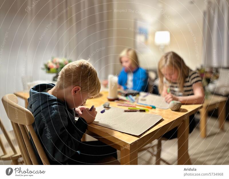 Drei Kinder malen am Esstisch Tisch Stift beschäftigt Beschäftigung Freizeit Kreativität zeichnen Kindheit Freizeit & Hobby Innenaufnahme Stifte Steine anmalen