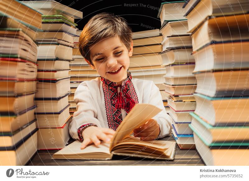 Hübsches kleines ukrainisches Kind blättert durch Buchseiten in einer Bibliothek. Grundschuljunge genießt das Lesen in einer Buchhandlung oder einem Buchladen