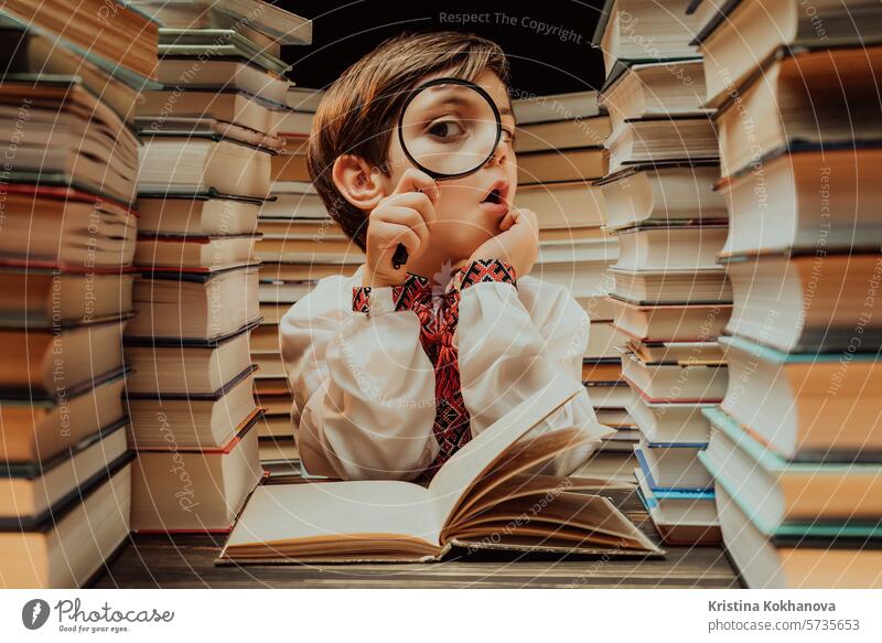 Kleine ukrainische Forscher Junge liest Buch mit Lupe in der Bibliothek. Cute clever Vorschüler spielen, studieren Wissen mit Instrument Bildung lernen