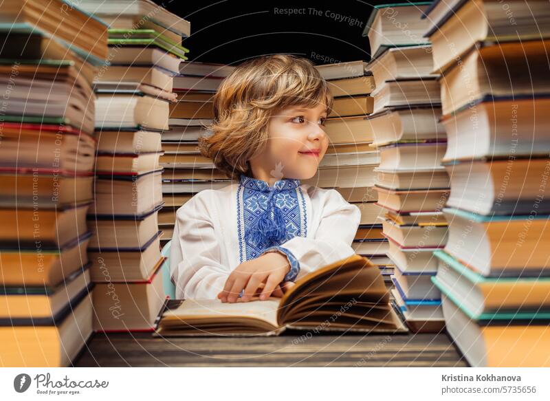 Porträt des hübschen kleinen ukrainischen Kindes mit Buch in der Bibliothek. Grundschuljunge posiert in Buchhandlung oder Buchladen. Bildung Junge lernen