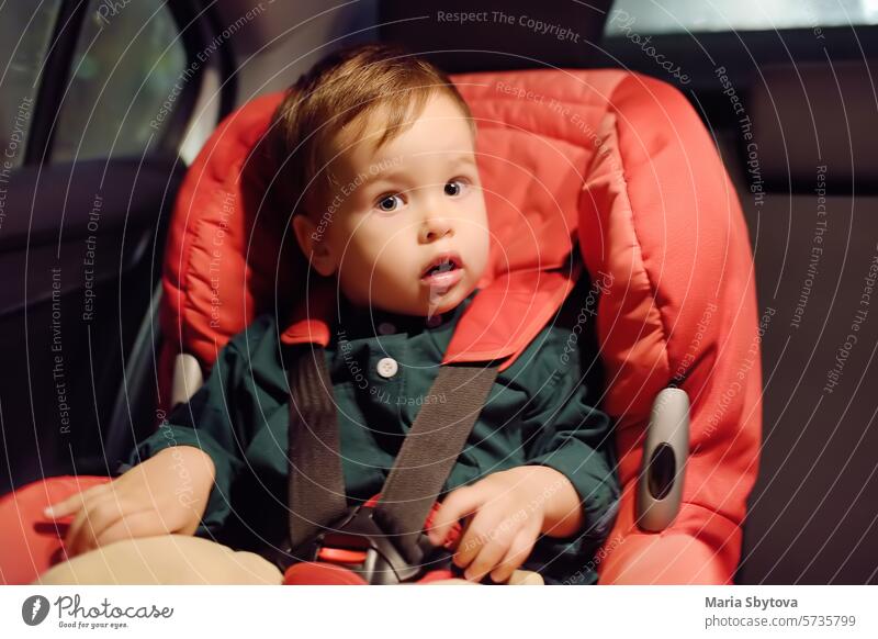 Nettes Kleinkind Junge ist in Autositz. Porträt der hübschen kleinen Kind während der Familie Road Trip. Kind verängstigt durch Reisekrankheit oder Reiten im Fahrzeug in der Nacht Zeit. Sicherheit Transport von Baby mit dem Auto.