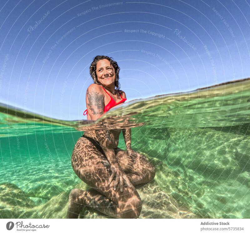 Gelassene Unterwasser-Szene mit lächelnder Frau im Sonnenlicht unter Wasser Muster fliegend Gelassenheit roter Badeanzug Freude ruhig Wasseroberfläche Lächeln