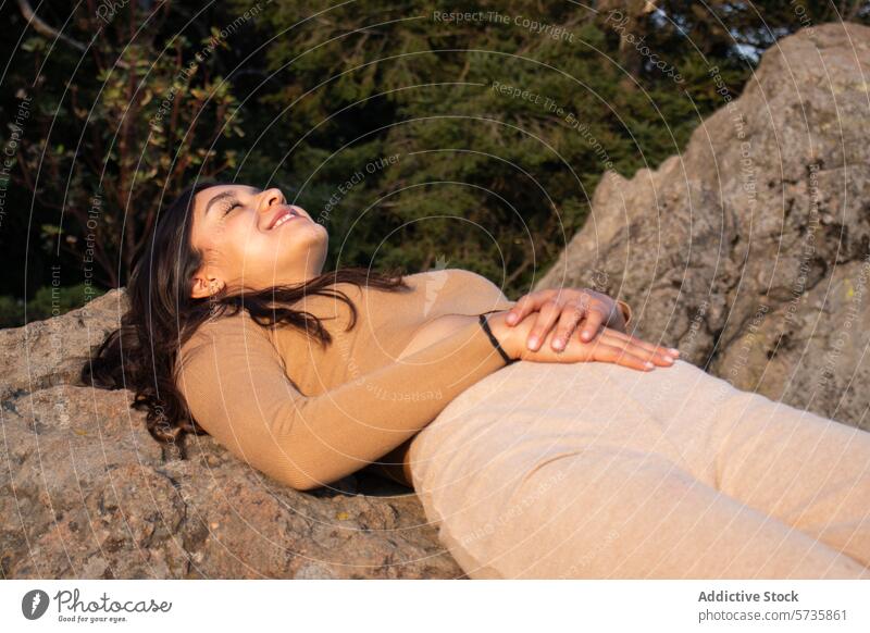Eine Person strahlt Glück aus, während sie sich auf einem Felsen zurücklehnt, umgeben von der ruhigen Schönheit eines natürlichen Waldes entspannt Frau Freude
