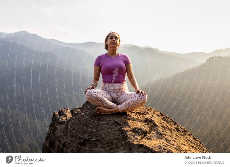 Eine Person findet inneren Frieden, während sie im Lotussitz auf einem Berggipfel meditiert, mit einem atemberaubenden Blick auf den Wald unter ihr Meditation