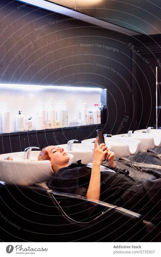 Entspannung in einem Friseursalon mit moderner Ausstattung Frau entspannend Smartphone Haarbehandlung Stuhl Salon Innenbereich wartend Haarpflege Schönheit