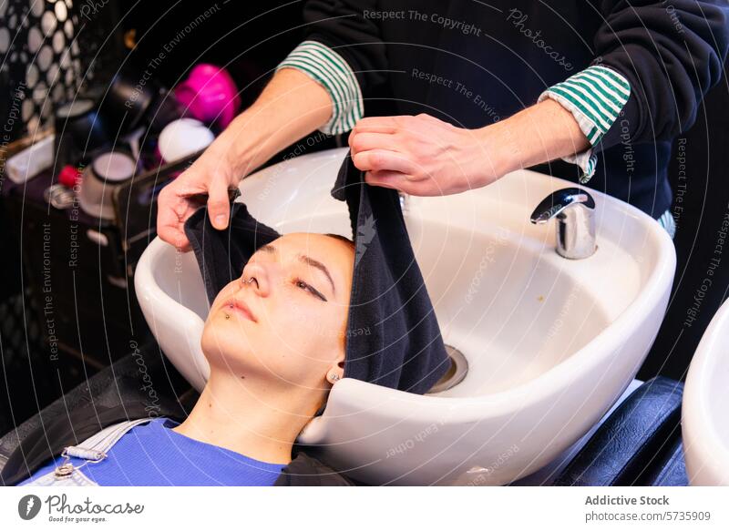 Eine Kundin entspannt sich während einer Haarwäsche im Salon Friseursalon Klient Haare waschen Handtuch Becken Waschbecken Pflege Komfort Haarpflege Schönheit
