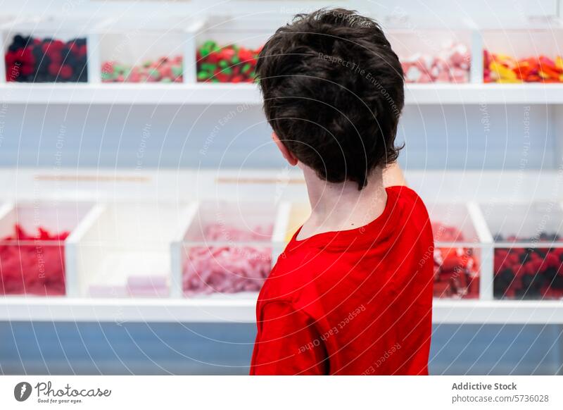 Junge Kundin wählt in einem Süßwarengeschäft Süßigkeiten aus Person rot Hemd hinten Bonbon Werkstatt farbenfroh Anzeige Wahl Varieté Kunde Konditorei süß
