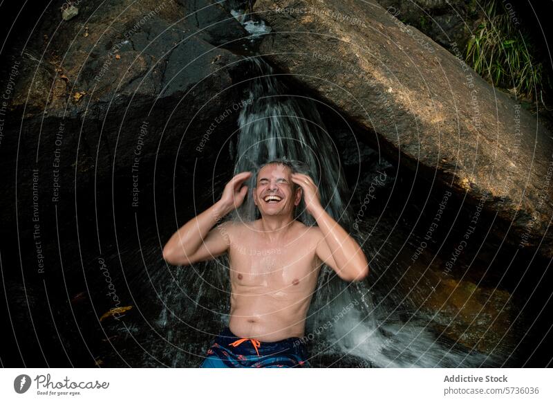 Ein Mann lacht vor lauter Freude, als er eine natürliche Wasserfalldusche im Herzen des üppigen Waldes von Langkawi genießt Lachen Dusche malaysia Natur