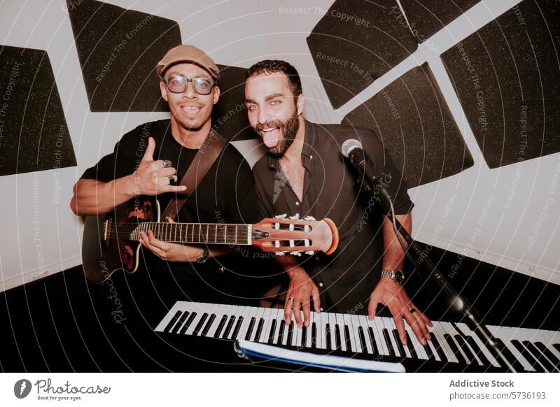 Zwei männliche Musiker mit Gitarre und Keyboard im Studio Band Stromgitarre Atelier in die Kamera schauen Leistung spielerisch Genuss Entertainment Künstler