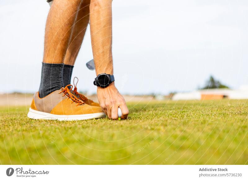 Golfer bei der Vorbereitung auf ein Spiel an einem sonnigen Tag Ball T-Stück Gras Rasen Sport Schuhe Kniestrümpfe Platzierung hockend Kurs Freizeit im Freien