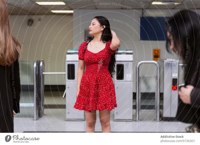 Junge Frau in rotem Kleid wartet an einer Transitstation asiatisch Warten Station stehen pulsierend urban lässig Geduld jung Körpersprache Drehkreuz Eingang