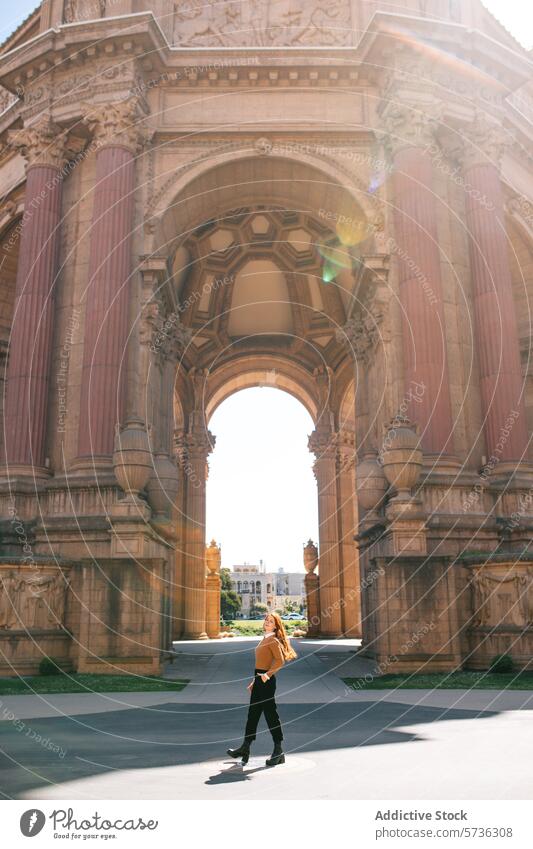 Eine Frau in legerer Kleidung geht selbstbewusst über das Gelände des Palace of Fine Arts und genießt die Frühlingssonne in San Francisco. lässig schlendern