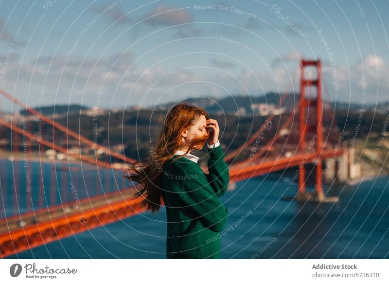 Ein nachdenklicher Moment, in dem eine Frau mit vom Wind zerzausten Haaren auf die Golden Gate Bridge blickt und damit den Geist San Franciscos im Frühling verkörpert