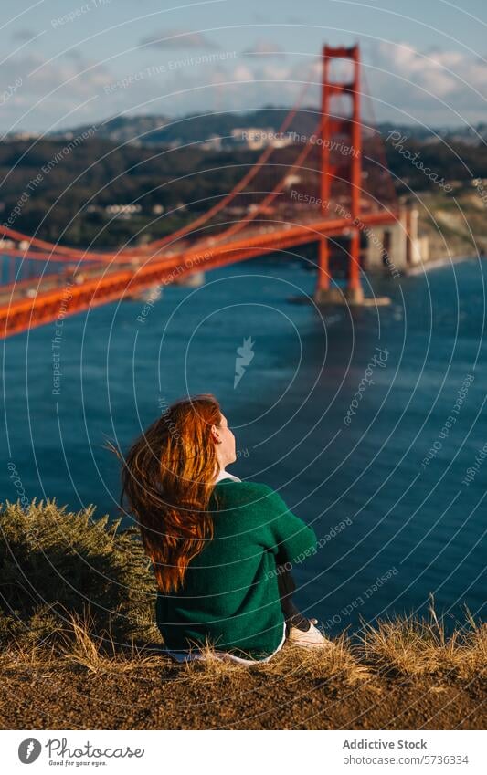 Eine Frau sitzt in Kontemplation und blickt auf die Golden Gate Bridge und die Skyline von San Francisco, eingetaucht in die Schönheit des Frühlings Ansicht