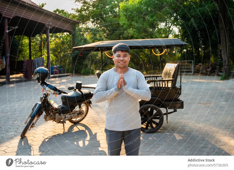 Junger Mann mit traditionellem Gruß im Freien neben einem Motorrad Namaste Lächeln Tuk-Tuk jung asiatisch lässig Bekleidung reisen Kultur Respekt höflich