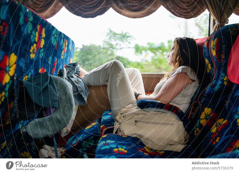 Frau entspannt sich auf einem bunten Bussitz während der Fahrt reisen Sitz Fenster entspannend Starrer Blick aussruhen farbenfroh Blumenmuster Rucksack