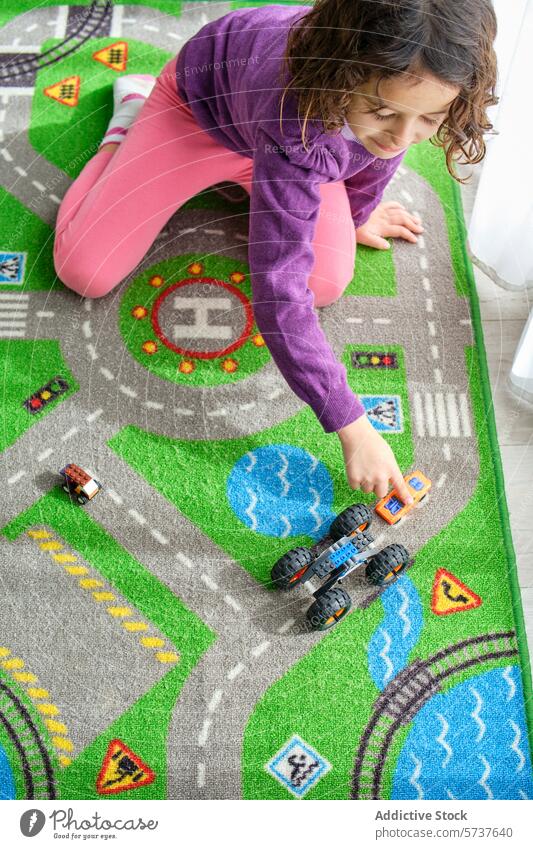 Mädchen spielt mit Spielzeugautos auf einer bunten Spielmatte spielen Kind PKW Spielteppich Vorstellungskraft im Innenbereich Kindheit Aktion farbenfroh