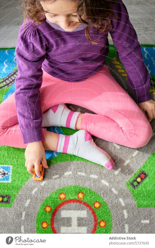Kind spielt mit Spielzeugauto auf einer bunten Spielmatte spielen PKW Mädchen Kreativität Genuss im Innenbereich Overhead Ansicht farbenfroh pulsierend
