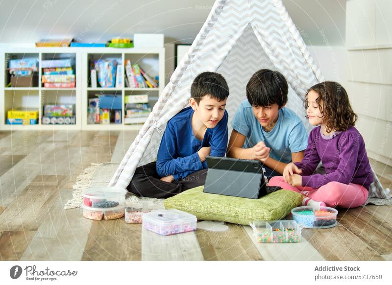 Geschwister genießen die Tablettenzeit in einem Spielzelt Kinder spielen Zelt im Innenbereich gemütlich Hama-Perlen Junge Mädchen vertieft