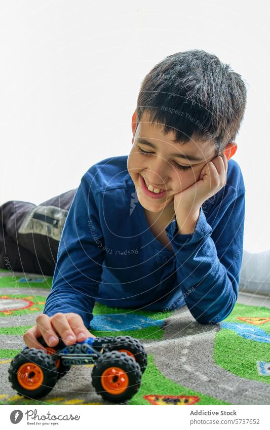 Junge lächelt, während er mit einem Spielzeugauto auf dem Boden spielt Kind spielen Spielteppich Lächeln Wegsehen Stock im Innenbereich Glück Freude Freizeit