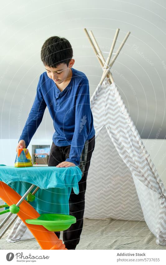 Junge spielt mit Eisen auf einem bunten Tuch Kind spielen bügelnd Spielzeug Vorstellungskraft Kindheit heimisch Tipi Spielzimmer Aktivität im Innenbereich