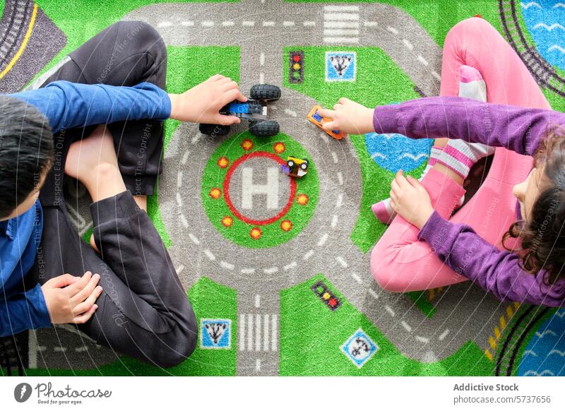 Kinder spielen mit Spielzeugautos auf einer bunten Spielmatte Spielteppich farbenfroh Ansicht von oben Hände pulsierend Thema der Straße Junge Mädchen