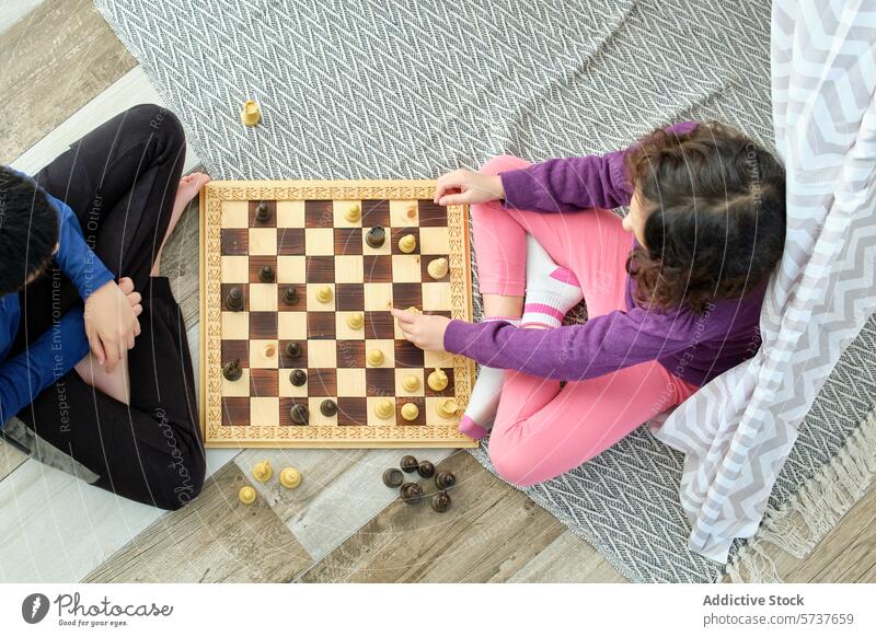 Zwei Kinder, die zu Hause eine Partie Schach spielen Spiel Holzplatte hölzern Strategie kognitiv Fähigkeit im Innenbereich Vorleger Junge Mädchen Overhead