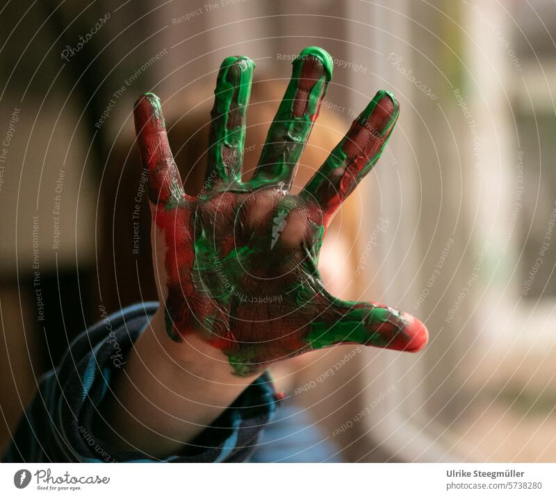 Ein Kind hält seine angemalte Hand in die Kamera Kreativ mit Kindern Leben mit Kindern Freude Spaß grün bunt rot Fingerfarbe lernen Kinderkunst Kunst
