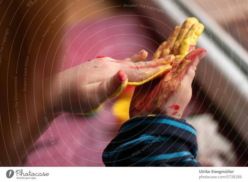 Ein Kind verreibt in seinen Händen gelbe Fingerfarbe Malen Kinder Kuns Kinderkunst Hand Freude Spaß Fenster Malen am Fenster Kreativ mit Kindern bunt