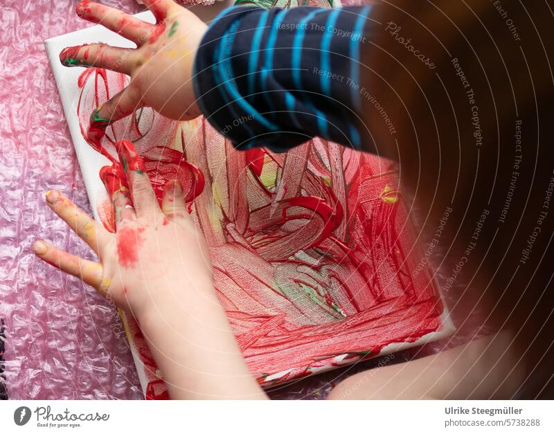 Ein Kind malt mit seinen Händen auf eine Leinwand Kinderkunst Malen mit Fingern Leben mit Kindern rot gelb bunt Hand Freude Spaß Fenstermalerei