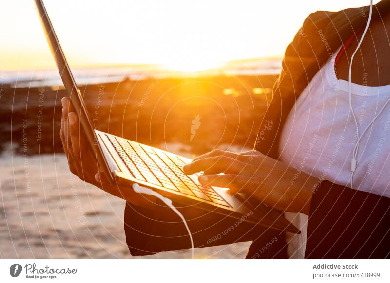Anonymer digitaler Nomade arbeitet am Laptop am Sunset Beach Sonnenuntergang Strand Arbeit abgelegen Kopfhörer Silhouette glühen Meer Technik & Technologie