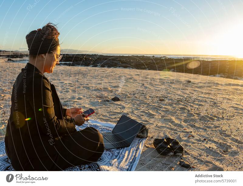 Entfernte weibliche Arbeit an einem Strand bei Sonnenuntergang digital Nomade Frau abgelegen Handy Laptop Smartphone Sand Technik & Technologie Meer Horizont