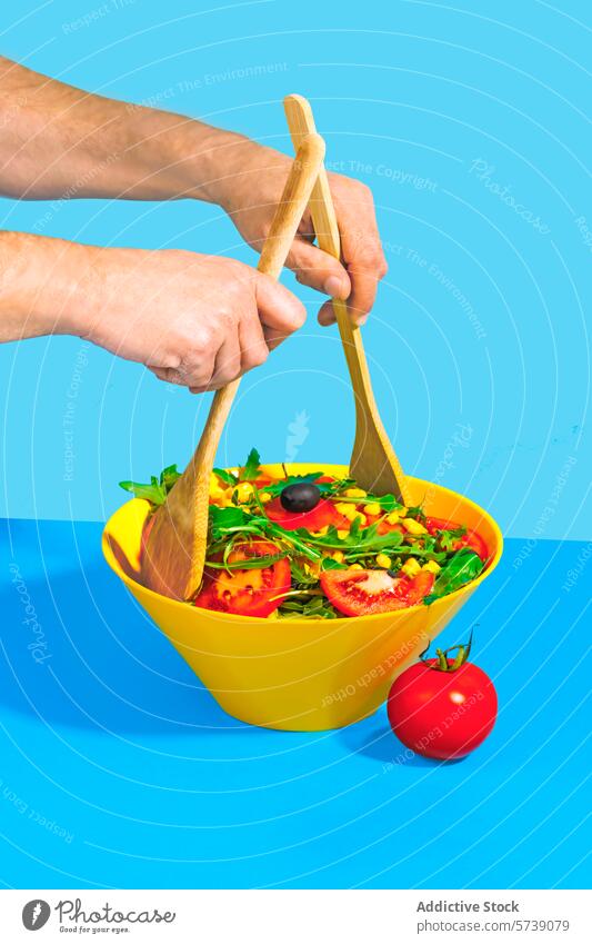 Frische Salatzubereitung mit Holzutensilien Salatbeilage frisch Vorbereitung hölzern Utensilien Hände gelb Schalen & Schüsseln blau Hintergrund Lebensmittel